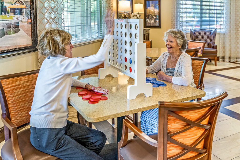 Senior friends playing connect four in activity room
